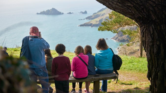 Visitors enjoying the view of Pudcombe Cove from the South West Coast Path at Coleton Fishacre, South Devon